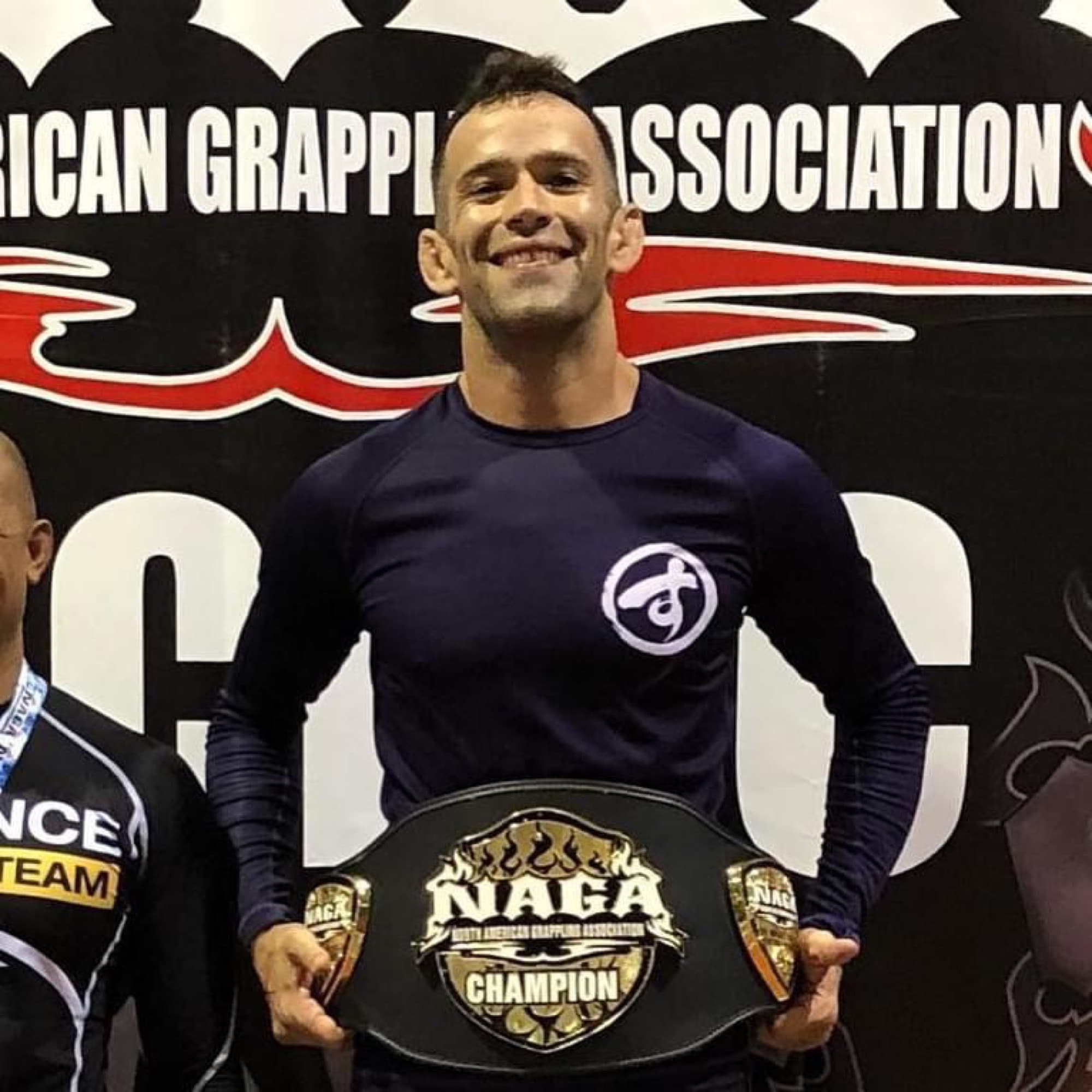 Joel Bouhey smiling, holding a NAGA champion belt.